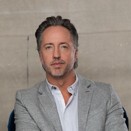 Portrait of a man with glasses wearing a gray shirt.