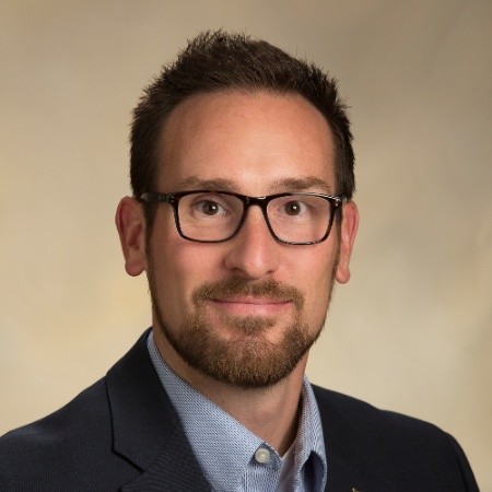Portrait of a man with glasses wearing a gray shirt.