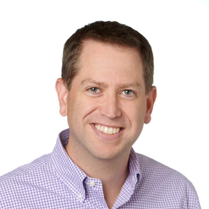 Portrait of a man with glasses wearing a gray shirt.